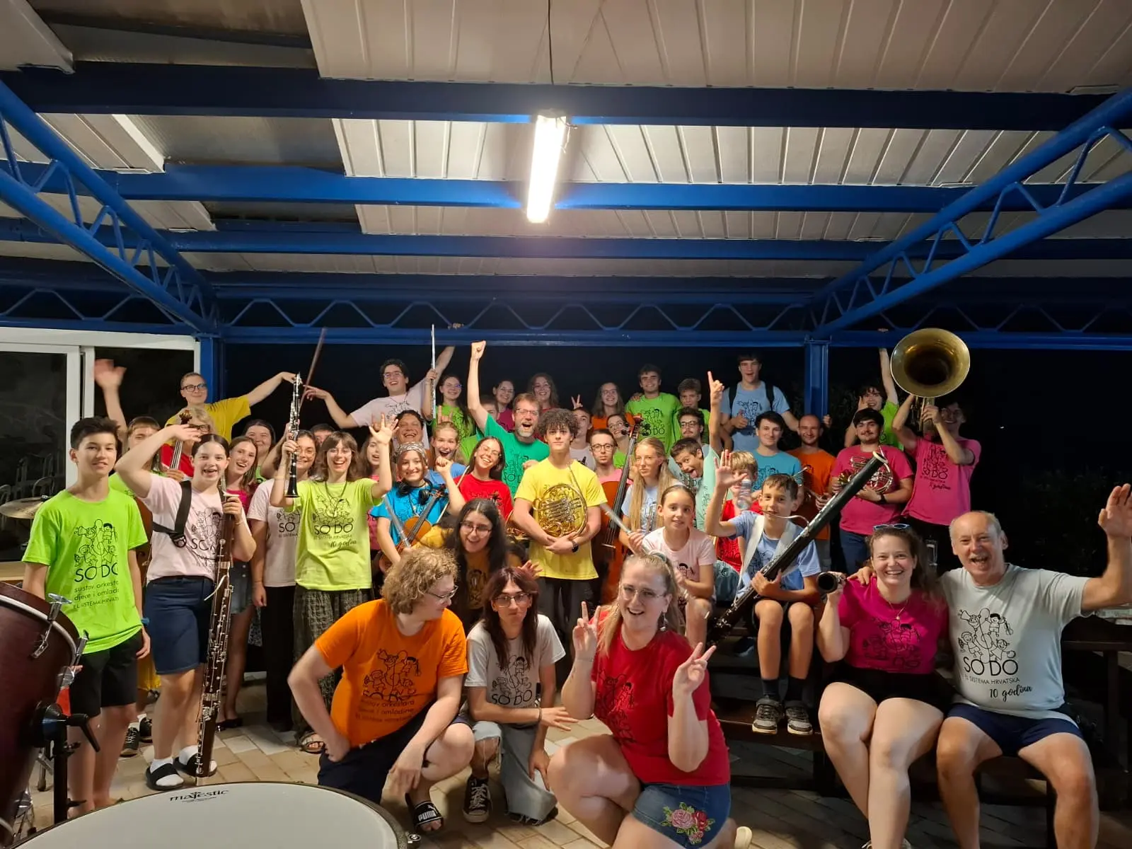 Skupina mladih glazbenika s instrumentima pozira nakon koncerta.