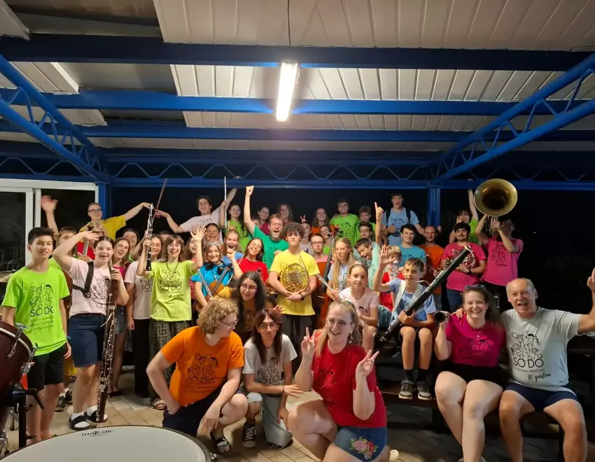 Skupina mladih glazbenika s instrumentima pozira nakon koncerta.